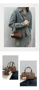 Detail of brown lychee grain leather Boston bag with plush bear charm and straps