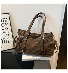 Close-up of dark brown tote bag featuring silver metal buckles and retro suede texture