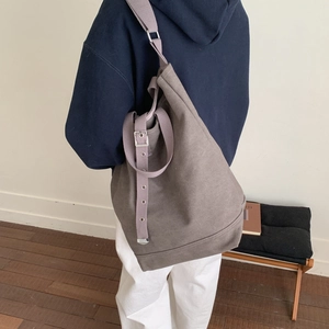 Détail de la bandoulière tissée réglable sur un grand sac seau en toile taupe