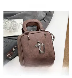 Detail of vintage brown tote bag featuring cross charm and metallic rivet accents