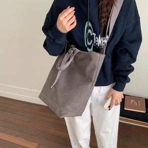 Détail du grand sac seau en toile gris foncé avec large bandoulière et œillets métalliques
