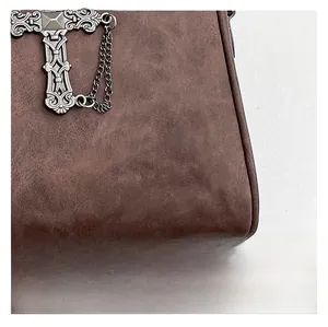 Macro shot of a vintage silver cross hardware and matte dark brown leather on the bag