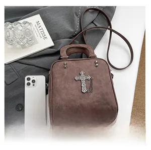 Detail of dark brown vintage faux leather handbag with silver cross and metal studs