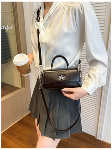 Detail view of dark brown patent leather handbag with silver twist lock and模特