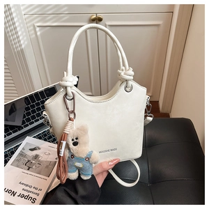 White leather bucket bag with top handles, knot detail and a plush bear charm decoration