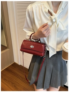 Detailed side view of a dark red patent leather handbag with silver metallic twist lock