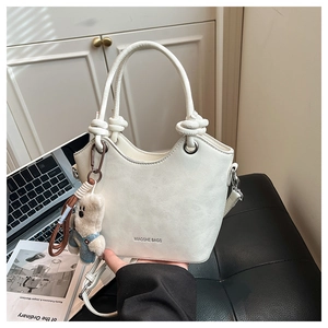 White fashion handbag with knotted handle and cute bear charm in lifestyle setting