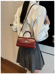 Detail of dark red glossy leather shoulder bag with silver metal swivel lock