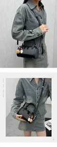 Detail of black cylindrical crossbody bag in denim fabric with decorative charms
