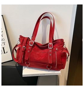 Macro shot of red faux leather tote featuring silver metallic buckles and decorative straps