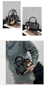 Detail view of a textured grey cylinder handbag with charms and a black handle strap