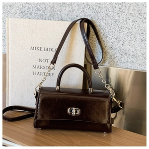 Detail of dark brown glossy leather handbag with silver twist lock and metal chain strap