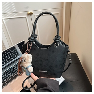 Detail of black tote bag with knotted handle, bear charm and white brand logo