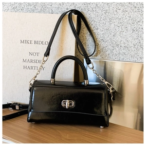 Detail showing shiny black leather texture with silver square twist lock and metal feet