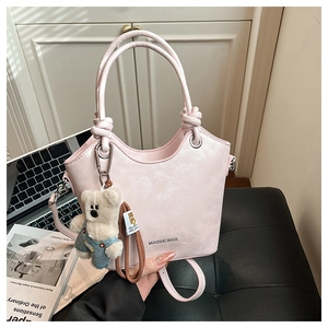 Pale pink bucket bag detail with round knotted handle and cute white bear charm