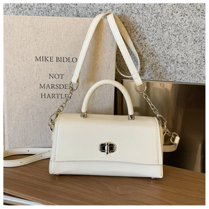 Macro detail of white leather handbag featuring a silver twist lock and chain strap accents