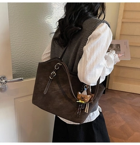 Detail of dark brown tote bag in matte leather with a cute plush bear charm accessory