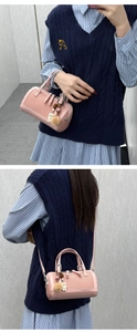 Detail of pink cylindrical handbag with cute plush bear pendant and textured leather finish