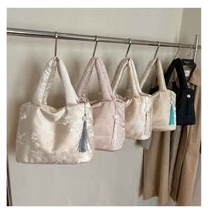 Détail de cinq sacs cabas en jacquard à motifs floraux et breloques à pompons sur cintres
