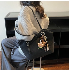 Detail of large black tote bag with cute bear charm and contrast stitching accents