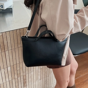 Detailed shot of black faux leather tote featuring round handles and silver hardware