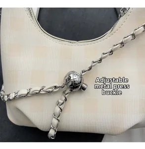 Detail of silver round push-button buckle for adjustable shoulder strap on beige bag