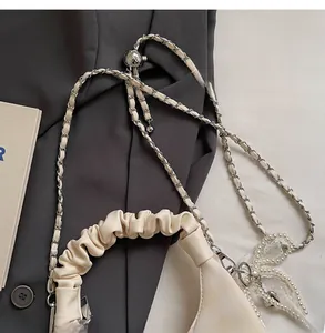Detail of adjustable chain strap with metal ball on a cream pleated crossbody bag