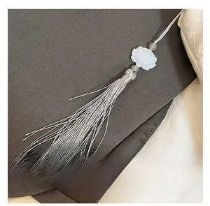 Détail d'un pendentif lotus blanc avec perles gris-brun et d'élégants longs glands