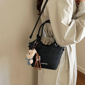Detail of a black textured bucket bag featuring a silver ring and cute bear pendant