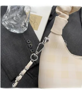Detail shot of silver metal chain hardware on a cream pleated crossbody handbag