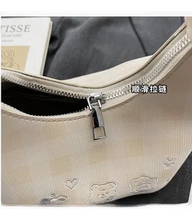 Detail of smooth metal zipper and grid texture with cute bear embroidery on beige bag