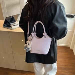 Pink bucket bag with knotted handle detail and cute bear charm shown in office setting