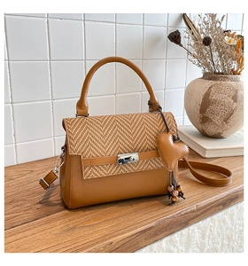 Detail of tan leather crossbody bag with herringbone texture and silver clasp closure