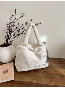 Détails de broderie florale sur un sac cabas en satin avec un gland de soie élégant