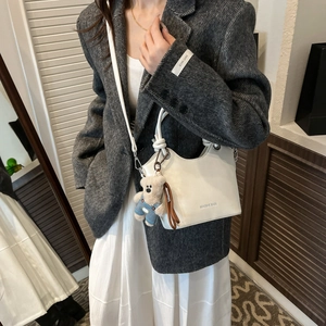 Detail of white bucket bag with MIAOSHE text and cute brown bear plush charm