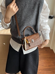 Brown leather crossbody bag with silver buckle and decorative wooden bead charm