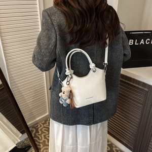 Detailed view of white leather bucket bag with plush bear charm and miaoshe inscription