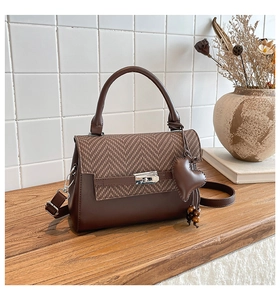 Detail of crossbody bag with herringbone weave flap and heart-shaped leather charm
