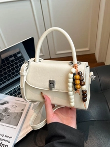 Chic cream leather handbag with beaded tassel and silver buckle shown in office setting