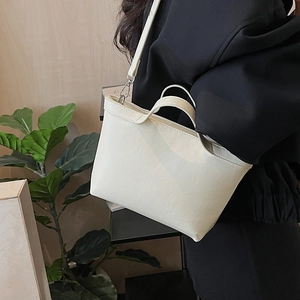 Lifestyle view of a cream faux leather tote bag showing size and minimalist shoulder strap