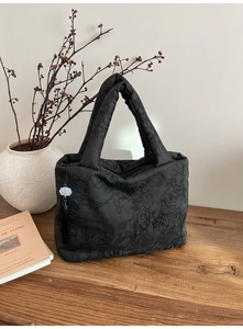 Détail d'un sac cabas noir avec broderie florale et pendentif à pampille fleurie