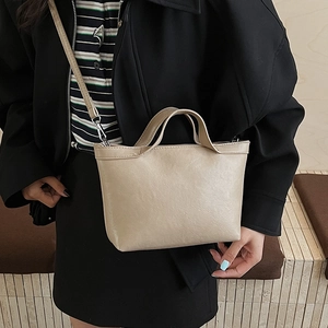 Detailed close-up of a minimalist beige tote bag with slim shoulder strap and top handles