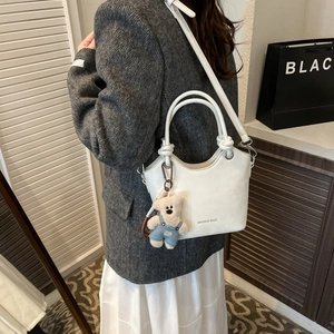 Detailed side view of white PU leather bucket bag with cute bear charm and logo print