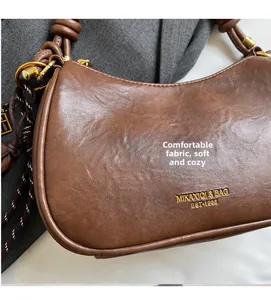 Close-up of brown lychee grain leather texture with gold logo and knotted handle detail