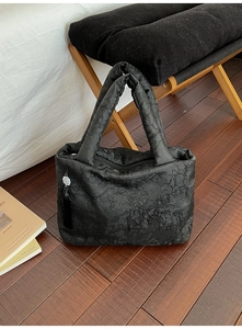 Détail du sac fourre-tout noir matelassé avec textures florales et pompon décoratif