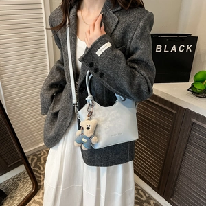 Detail of light blue bucket bag with cute bear charm and adjustable strap for women