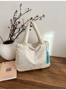 Détails du sac cabas en soie avec broderies dorées et pompon bleu de style chinois