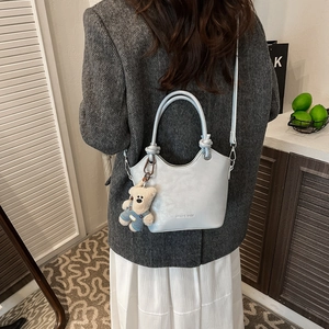 Light blue PU leather bucket bag with teddy bear charm shown as a stylish crossbody style