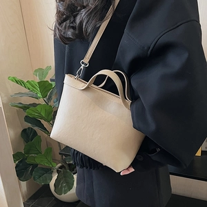 Detail of minimalist beige tote bag with slim shoulder strap and matte leather finish