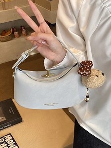 Light blue half-moon leather shoulder bag with gold clasp and plush dog charm accessory
